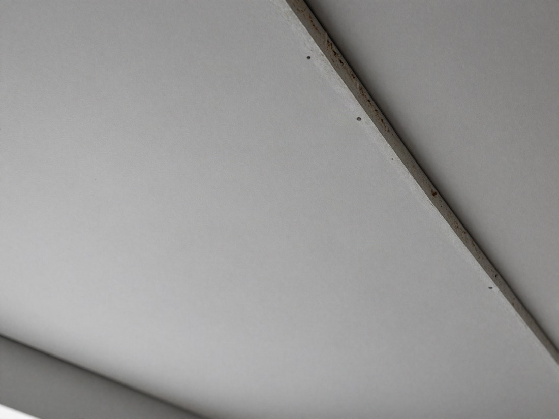 Pale grey fibrous insulating board ceiling panel with screw fixings